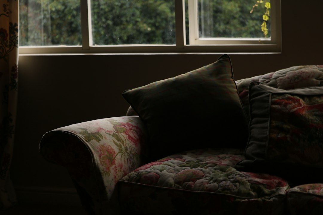 A floral patterned sofa with pillows near a window